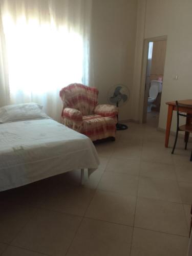 a bedroom with a bed and a chair and a window at Villa Xhelalit large ensuite rooms in Durrës