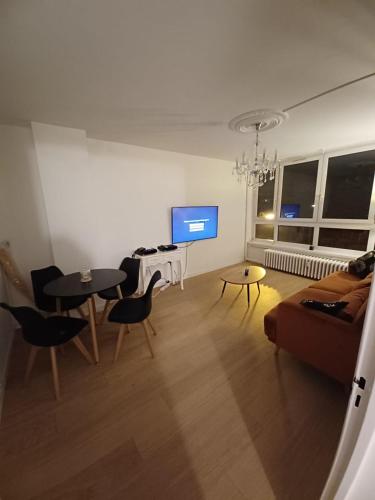 - un salon avec un canapé, des tables et une télévision dans l'établissement Appartement proche gare et petit déjeuner, à Tourcoing