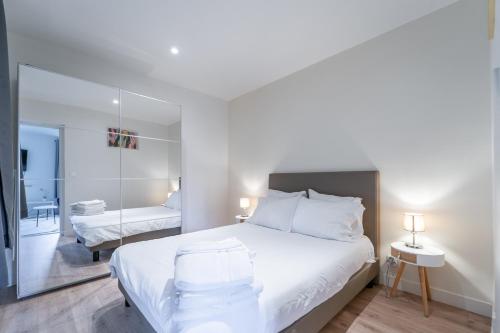 une chambre blanche avec un lit et un miroir dans l'établissement GH Apartment Pasteur-Montparnasse, à Paris