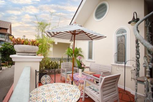 a patio with a table and chairs and an umbrella at Pran At Kumuang Boutique House in Chiang Mai