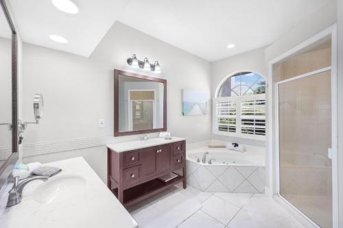 a white bathroom with a sink and a tub and a mirror at Waterfront home on key lot with pool and sundeck in Marco Island