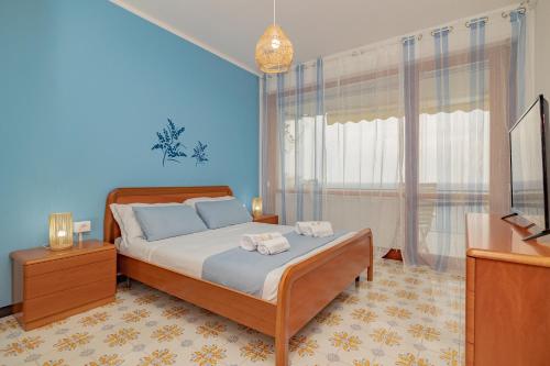 チェルヴォにあるMimosa Blu con vista mare terrazza - Wi Fi - AC - Parcheggioの青い壁と窓のあるベッドのある寝室