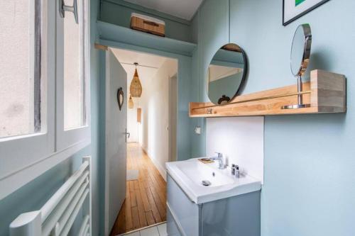 une salle de bain avec un lavabo et un miroir dans l'établissement Appartement élégant et moderne, à Paris