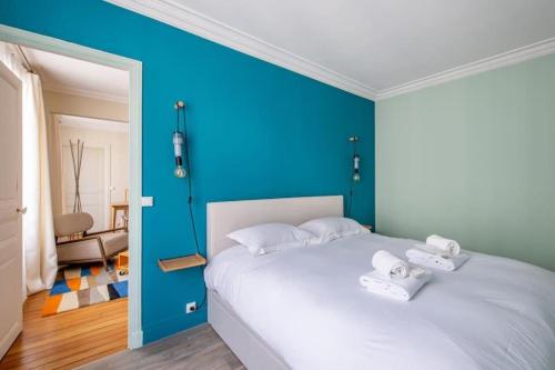 - une chambre avec un mur bleu et un lit blanc dans l'établissement Appartement élégant et moderne, à Paris