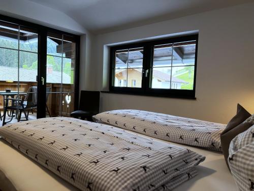 two beds in a room with two windows at Ferienwohnungen Kirchenwirt in Thiersee