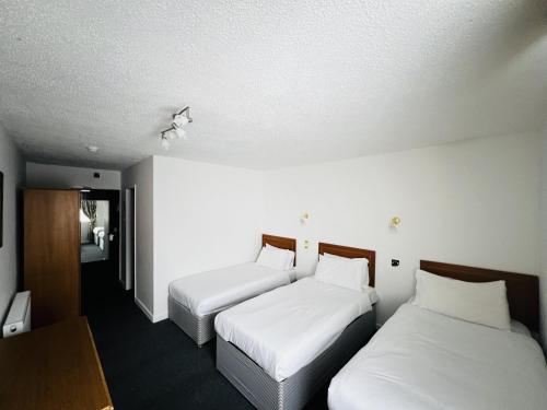 two beds in a hotel room with white sheets at Ox Hotel Carlisle in Carlisle