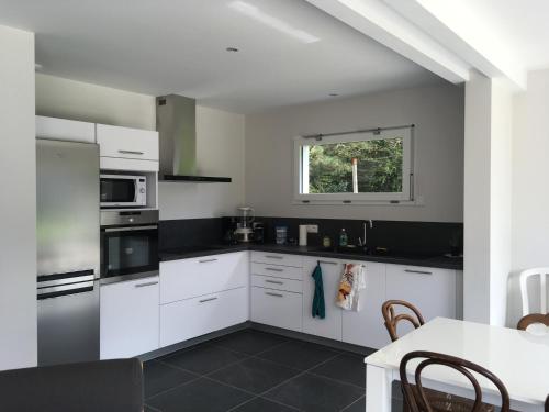 une cuisine avec des armoires blanches, une table et une fenêtre dans l'établissement Maison FONGRAIN, à Annecy