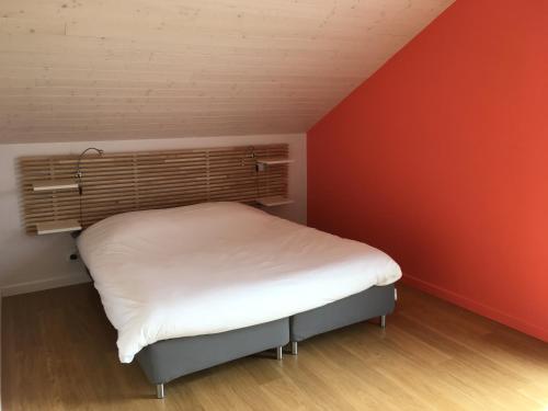- un petit lit dans une chambre dotée d'un mur rouge dans l'établissement Maison FONGRAIN, à Annecy