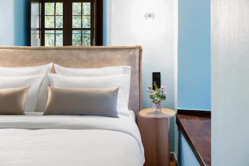 a bed with white sheets and pillows in a room at Kenta Mountain Hotel & Gastrobar in Portariá