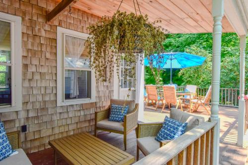 a porch with chairs and a table and an umbrella at Short drive to town and popular beaches in Orleans