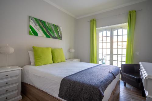 a bedroom with a bed with green pillows and a television at EnSuite 5 Verde Rochedo in Santo Isidoro