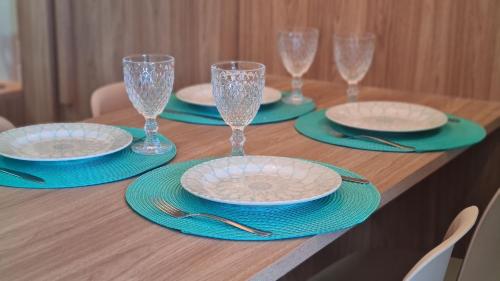 a wooden table with plates and wine glasses on it at Flats Tramonto - By EasyHost in João Pessoa