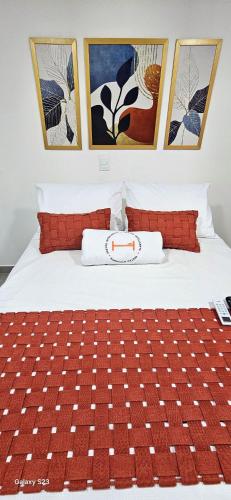 a bed with red and white pillows and paintings at Flats Tramonto - By EasyHost in João Pessoa