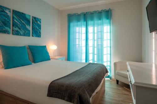 a bedroom with a bed and a chair and a window at EnSuite 1 Azul Rochedo in Santo Isidoro