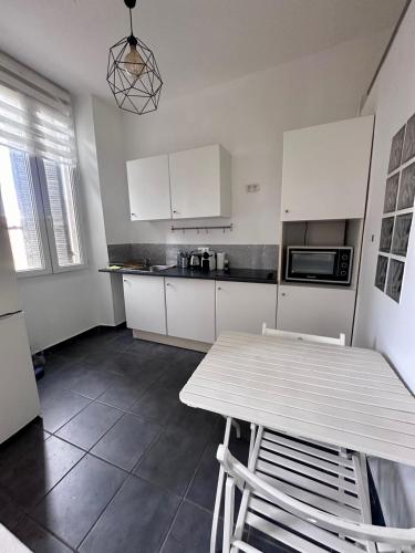 une cuisine avec des armoires blanches et une table avec des chaises dans l'établissement Joli Appartement aux Chartreux - Calme & lumineux, à Marseille