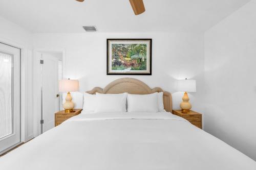 a white bedroom with a large bed and two lamps at The Palm Grove in West Palm Beach