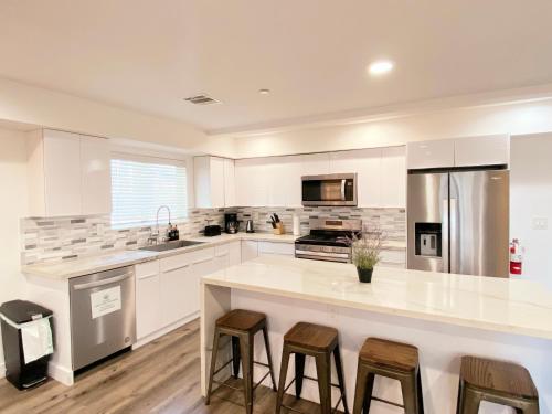 a kitchen with white cabinets and a large island with bar stools at Modern 3BR Home in Mid-City in Los Angeles