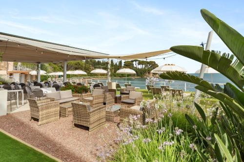 a patio with chairs and tables and umbrellas at Hotel Villa Domizia in Porto Santo Stefano