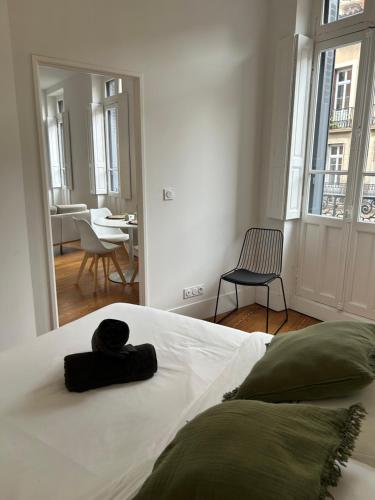 un lit blanc avec un chapeau noir posé dessus dans l'établissement Le Toulousain 102 - Appartement Cosy en Hypercentre - Quartier Jeanne d'Arc, à Toulouse