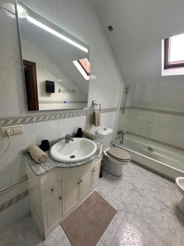 a bathroom with a sink and a toilet and a mirror at Ático en el Centro de Cambados in Cambados
