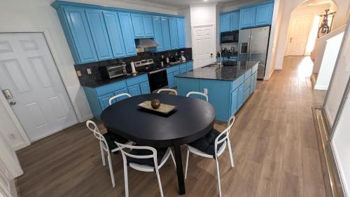 a kitchen with blue cabinets and a black table and chairs at Rent W Palm Beach in West Palm Beach