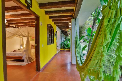 a room with a bed and a room with yellow walls at Pousada Jardim Das Margaridas in Trancoso