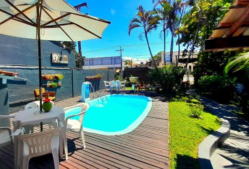 a swimming pool with a table and an umbrella at Pousada do Rock in Arraial d'Ajuda