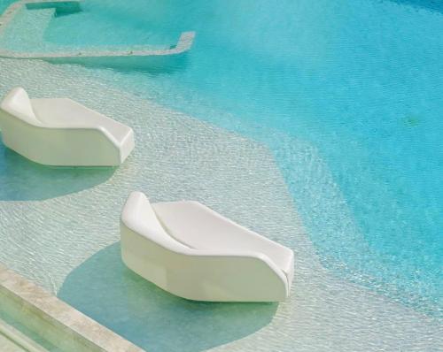 two white chairs sitting on the water in a pool at Veranda Pattaya Sea View Jomtien Beach Front วิวทะเล พัทยา จอมเทียน in Na Jomtien