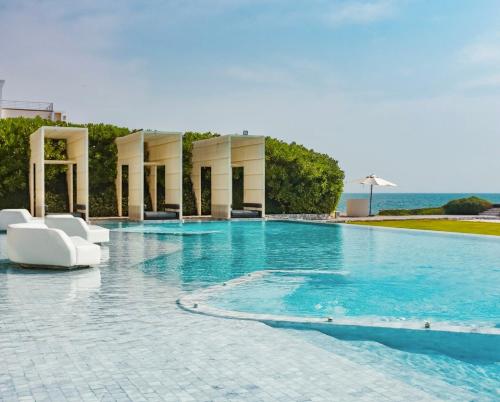 a swimming pool with white chairs and the ocean at Veranda Pattaya Sea View Jomtien Beach Front วิวทะเล พัทยา จอมเทียน in Na Jomtien