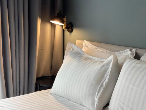 a bed with white pillows in a bedroom with a lamp at Ambassador Skyline Apartments in Tirana