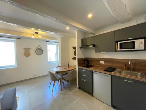 une cuisine avec un évier et une table avec des chaises dans l'établissement Appartement calme et cosy à deux pas du centre ville, à La Crau