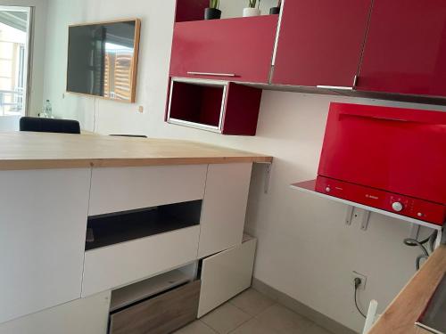 a kitchen with red cabinets and a microwave at Tout confort prêt de la défense in Bezons