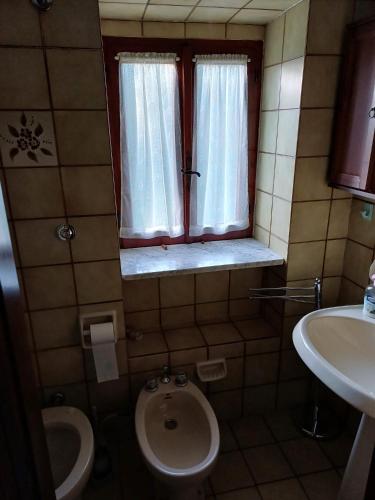 a bathroom with a toilet and a sink and a window at Casa nel verde !!! in Falconara Albanese