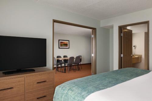 a hotel room with a bed and a flat screen tv at Wingate by Wyndham Louisville East in Louisville