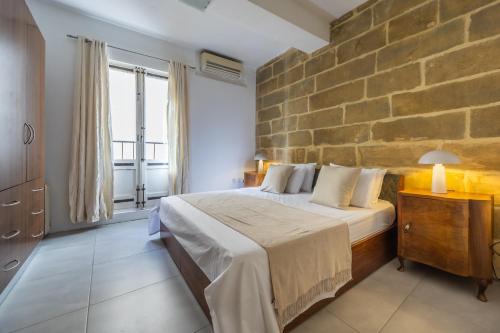 a large bedroom with a large stone wall at Stunning 1-Bed Apartment In Heart of Valletta in Valletta