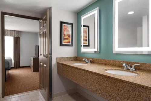 a bathroom with two sinks and two mirrors at Wingate by Wyndham Louisville East in Louisville