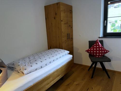 a small bedroom with a bed and a chair at Ferienwohnungen Kirchenwirt in Thiersee