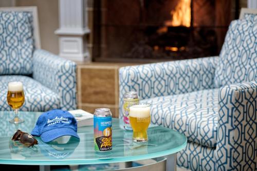 a glass table with two glasses of beer and a hat at Beach House Hotel at Hermosa Beach in Hermosa Beach