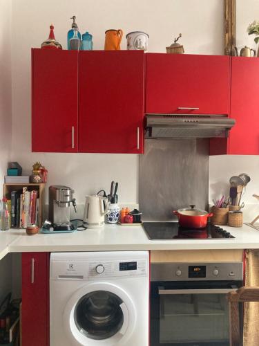 - une cuisine avec des placards rouges et un lave-linge dans l'établissement Appartement de charme, à Lille