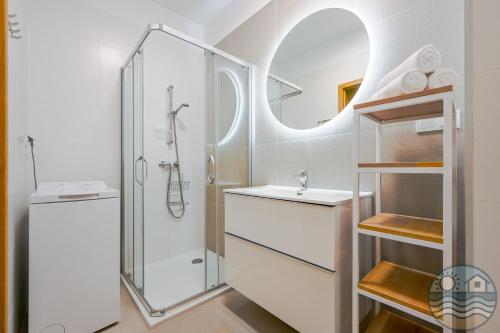 a bathroom with a shower and a sink and a mirror at Dąbki Beachfront Retreat in Dąbki