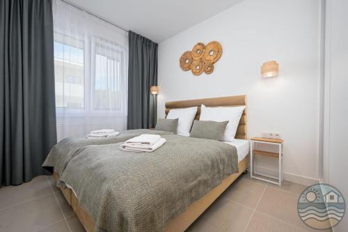 a bedroom with a bed with two towels on it at Dąbki Beachfront Retreat in Dąbki