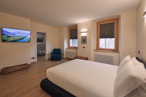 a bedroom with a white bed and a tv on the wall at Le Corti Dei Sassi in Berbenno di Valtellina