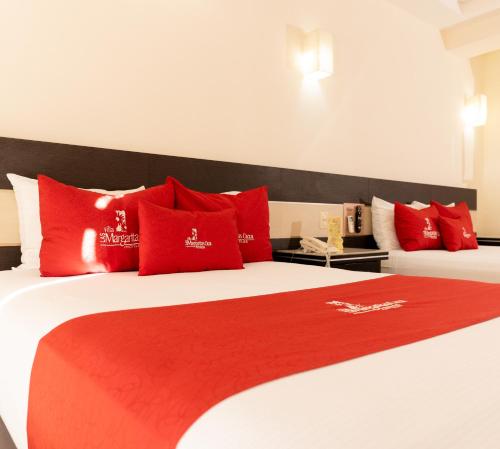 two red pillows on a bed with a red blanket at Villa Las Margaritas Caxa in Xalapa