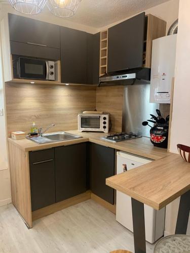 une cuisine avec un évier et un micro-ondes dans l'établissement Appartement Hyper centre historique Toulouse capitole cosy, à Toulouse