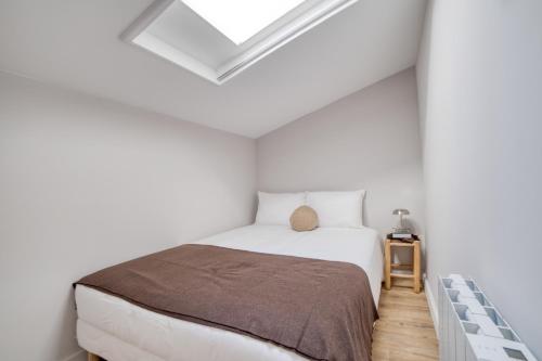 - une chambre blanche avec un lit et une lucarne dans l'établissement Bel appartement au dernier étage - Megève, à Megève