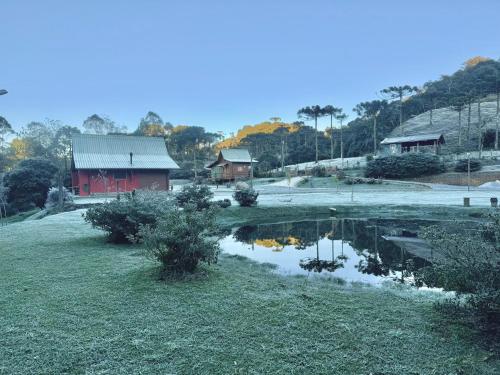 a farm with a red building and a pond at Vila Vert - Rancho Queimado - SC in Rancho Queimado