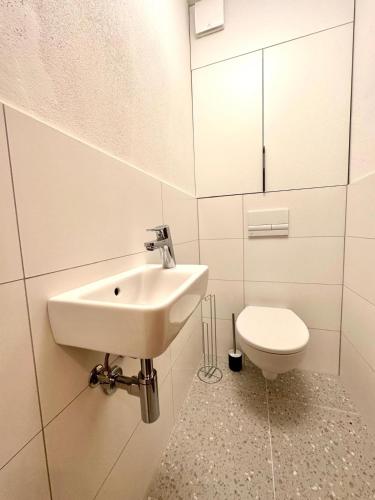 a white bathroom with a sink and a toilet at City appartment AC & Parking in Prievoz