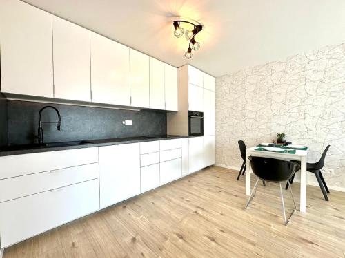 a kitchen with white cabinets and a table and a sink at City appartment AC & Parking in Prievoz