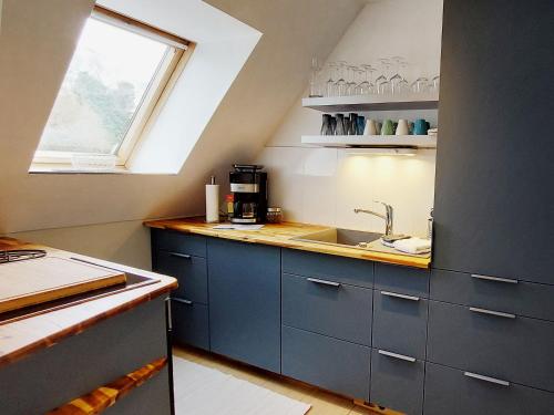 eine Küche mit blauen Schränken, einem Waschbecken und einem Fenster in der Unterkunft Backstage Apartment Kiel-Holtenau in Kiel