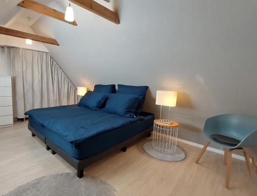 ein Schlafzimmer mit einem blauen Bett und einem Stuhl in der Unterkunft Backstage Apartment Kiel-Holtenau in Kiel